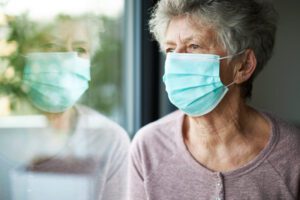 senior in mask looking out window