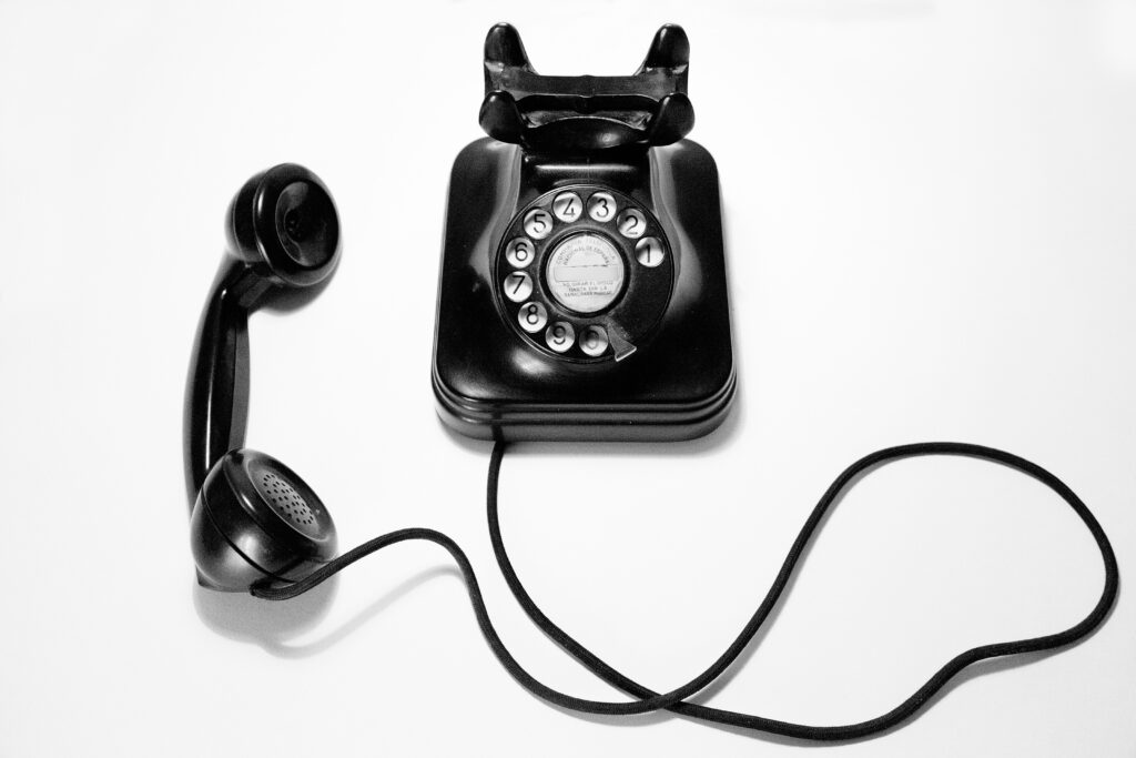 black rotary phone on white backdrop